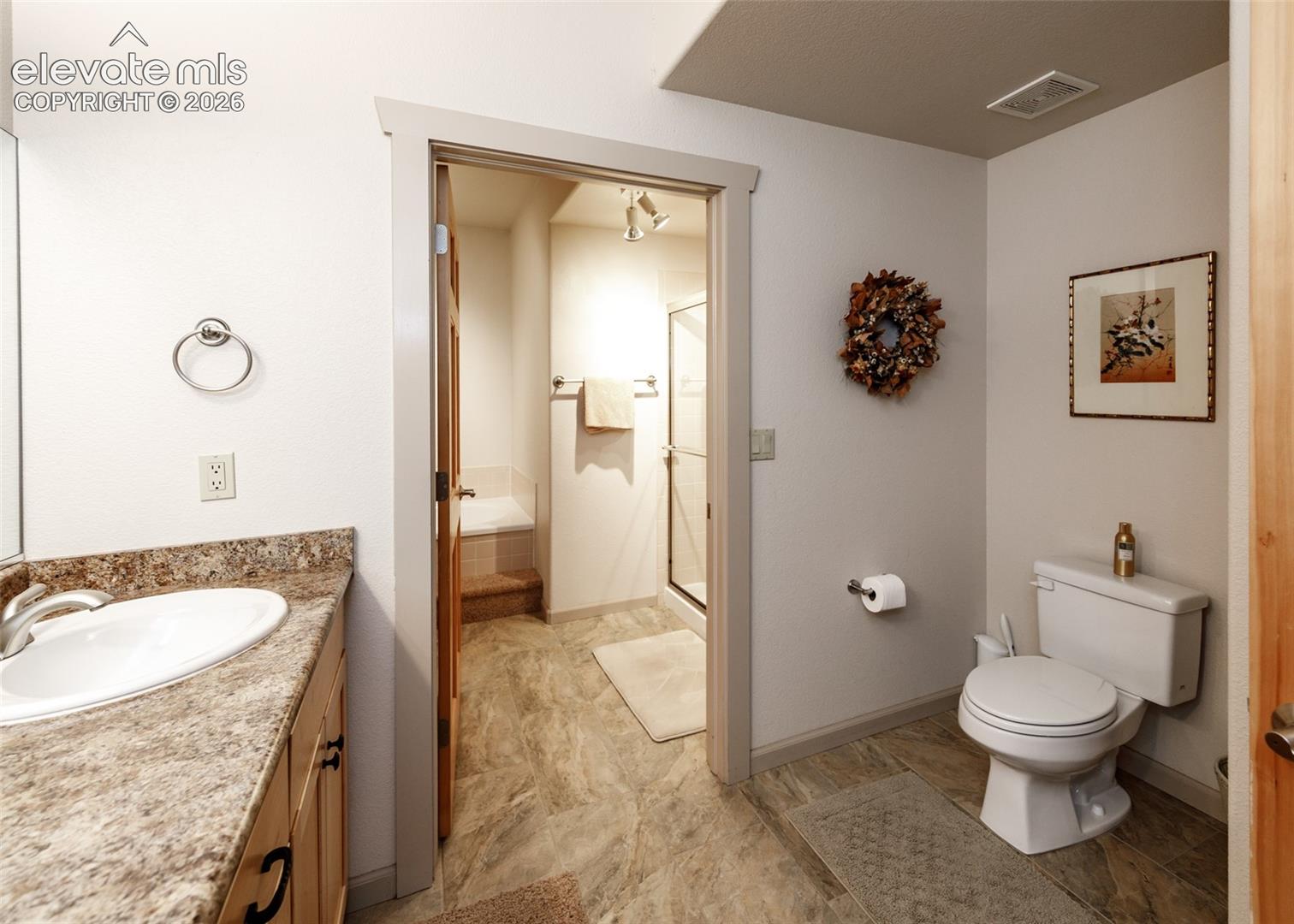 Lower level 5-piece bathroom featuring double vanity and beautiful tiled flooring.