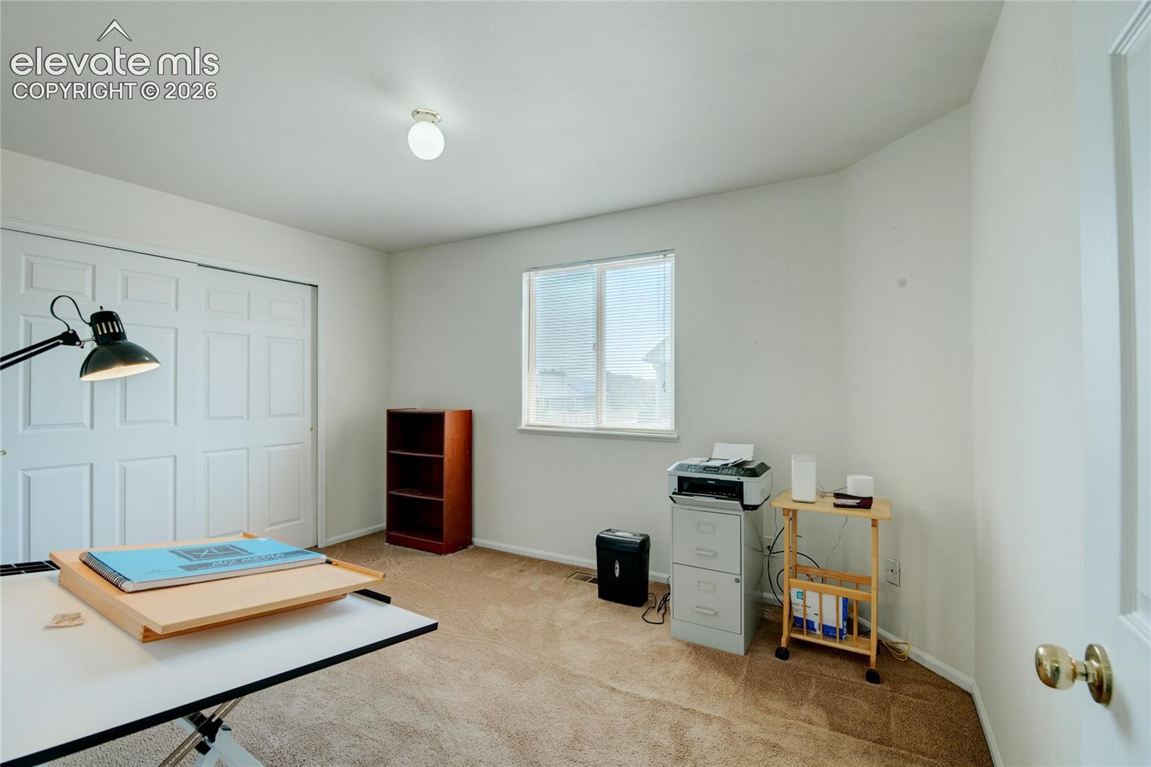 Interior room featuring neutral wall paint, light brown carpet, and a window with horizontal blinds