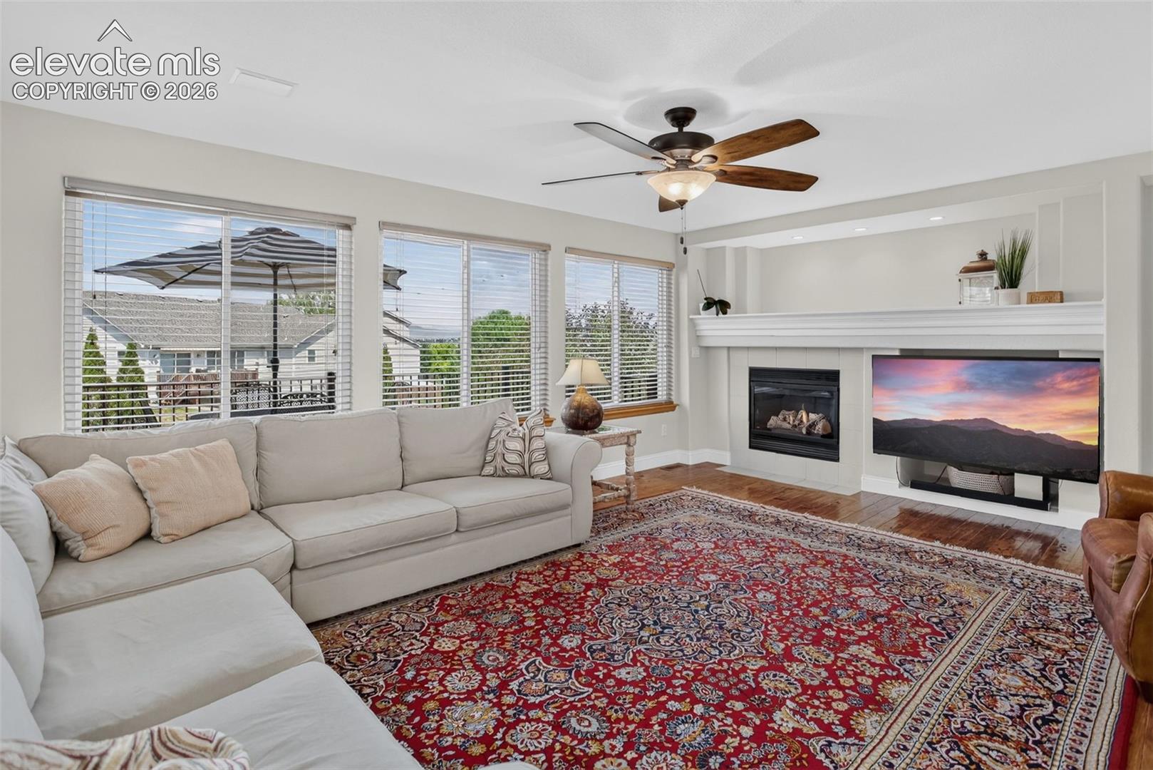Living room featuring hardwood-finish flooring and a ceiling fan with integrated lighting