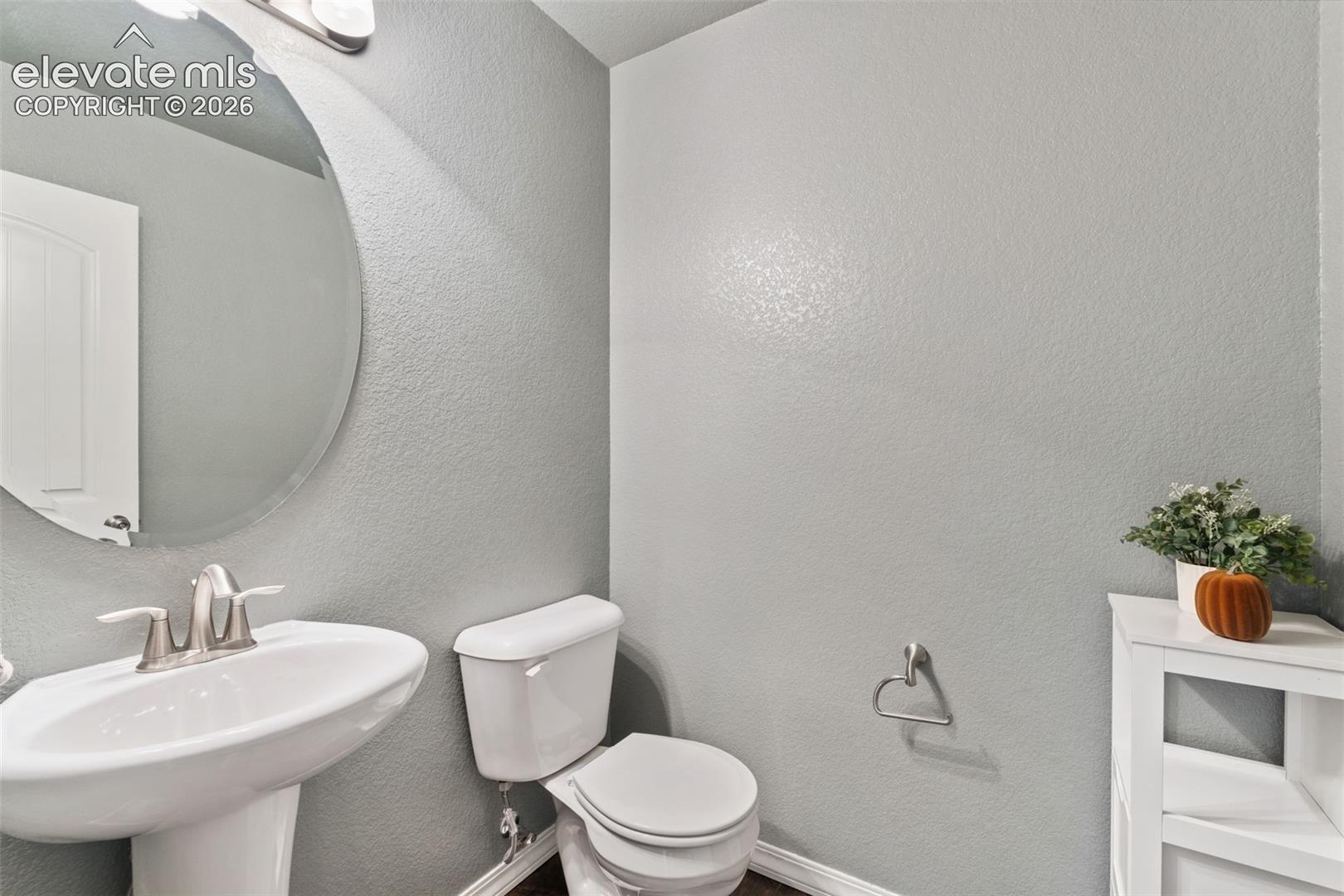 Pedestal sink with brushed nickel faucet, oval frameless mirror, and overhead vanity lighting