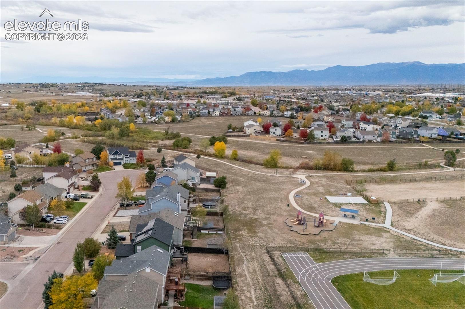 Aerial perspective featuring open space, a paved track, outdoor recreational structures, and mountain scenery