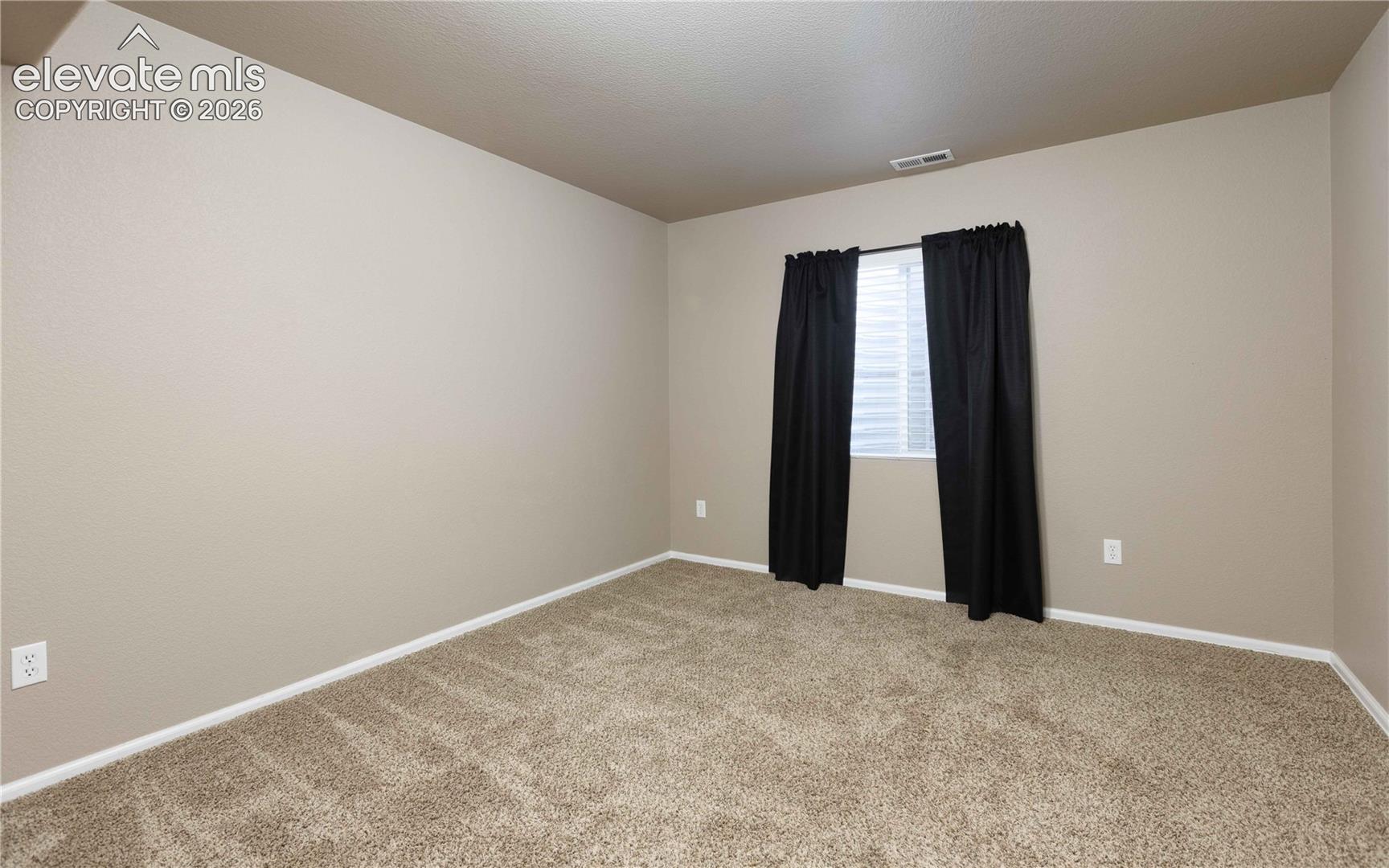 Neutral-toned wall finish featuring plush carpeting and a single window with horizontal blinds