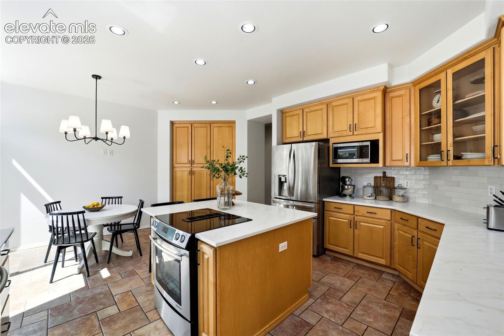 Updated kitchen featuring stainless steel appliances, light wood cabinetry, quartz countertops, and a subway tile backsplash