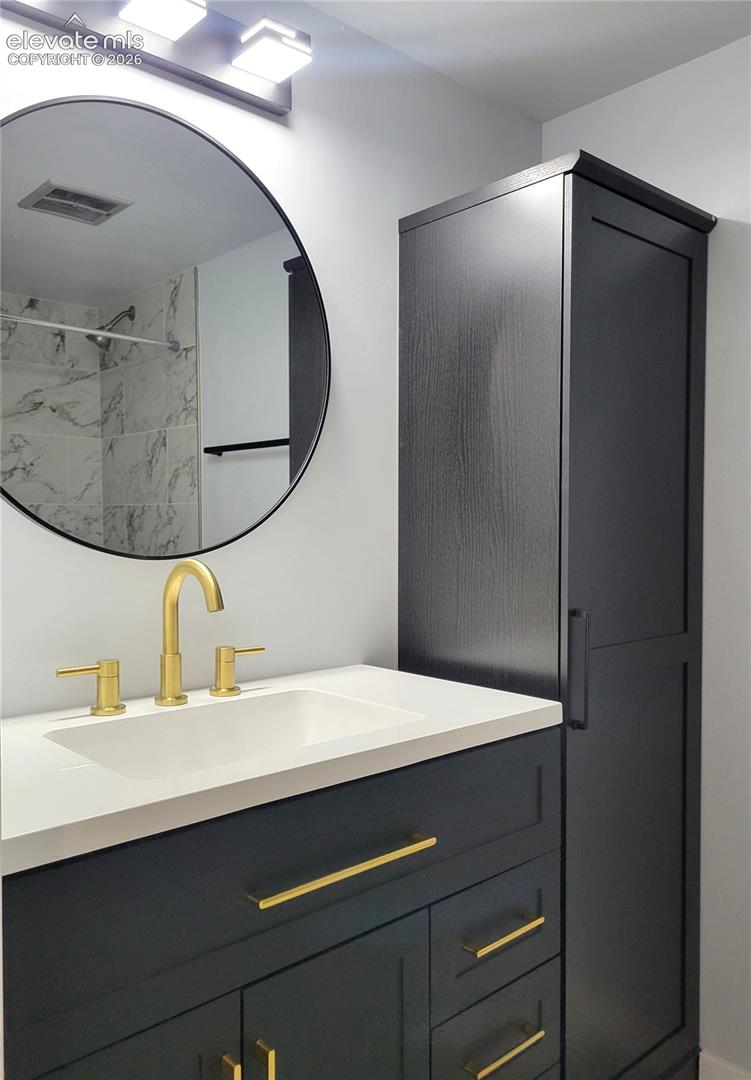 Modern bathroom vanity with matte black cabinetry, a white countertop, and gold-finish fixtures
