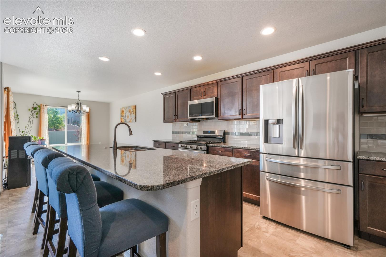 Kitchen with large island, granite countertops, gas range, abundant cabinets, views into dining room