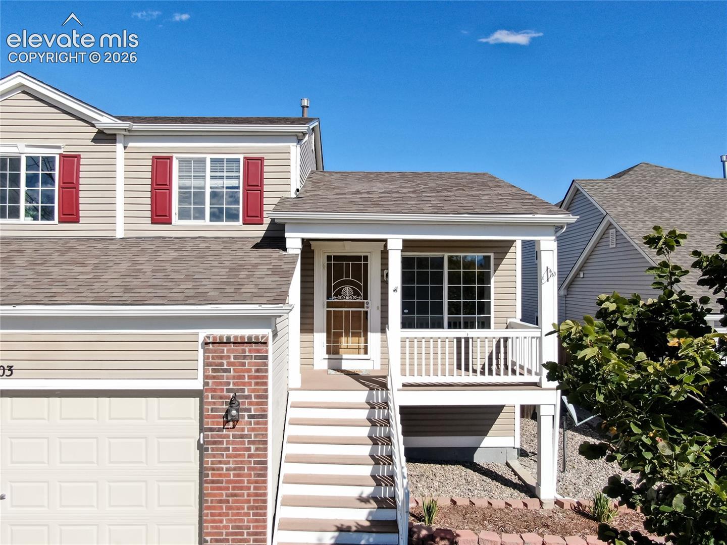 Step up to a welcoming, covered front entry porch featuring white railings and a decorative storm door