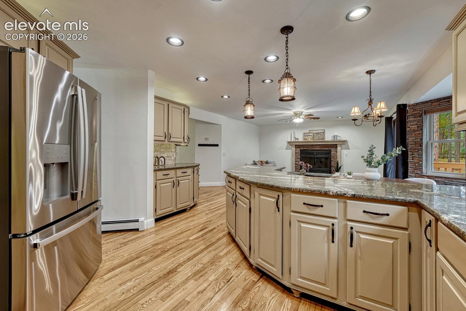 Kitchen featuring a curved island with stone countertops, stainless steel appliances, wood-finish flooring, custom cabinetry, and recessed lighting