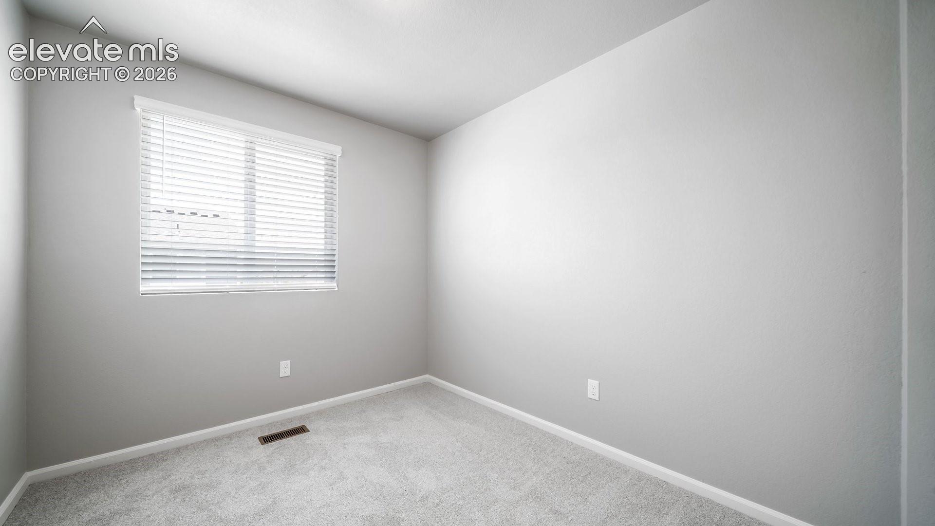 Neutral-toned interior space featuring light-colored wall paint, plush carpeting, and a window with horizontal blinds
*photos of a model home*