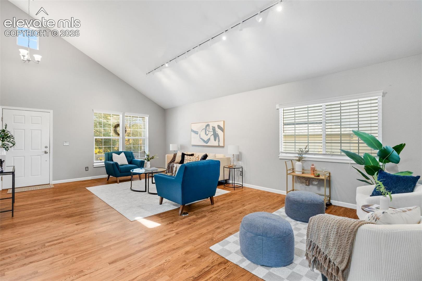 Vaulted ceilings featuring recessed track lighting, wood-finish flooring, and expansive windows
