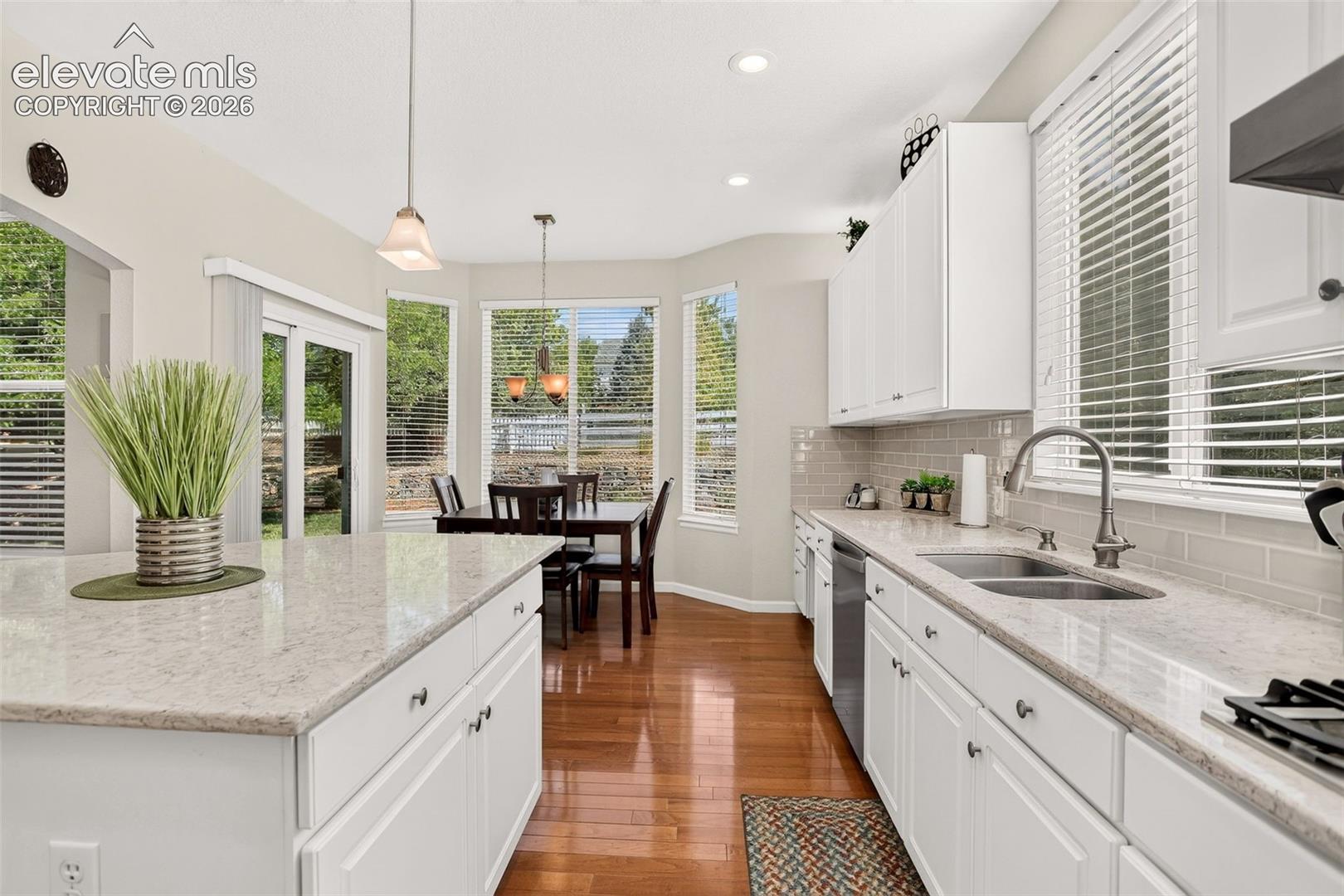 Gourmet kitchen featuring white cabinetry, light-toned countertops, and wood-finish flooring
