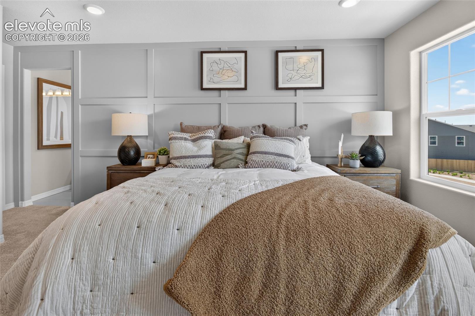 Room featuring a light grey accent wall with custom grid-pattern millwork, recessed ceiling lighting, and a multi-pane window