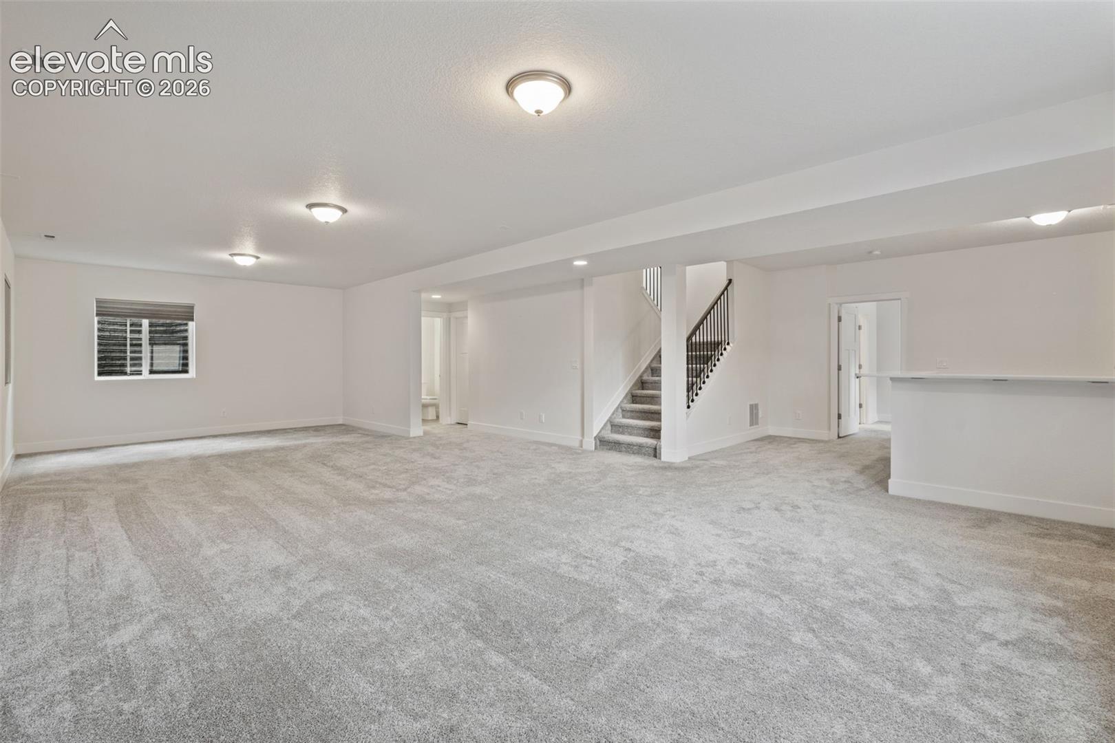 Spacious finished lower level featuring recessed lighting, light gray carpeting, and a powder room