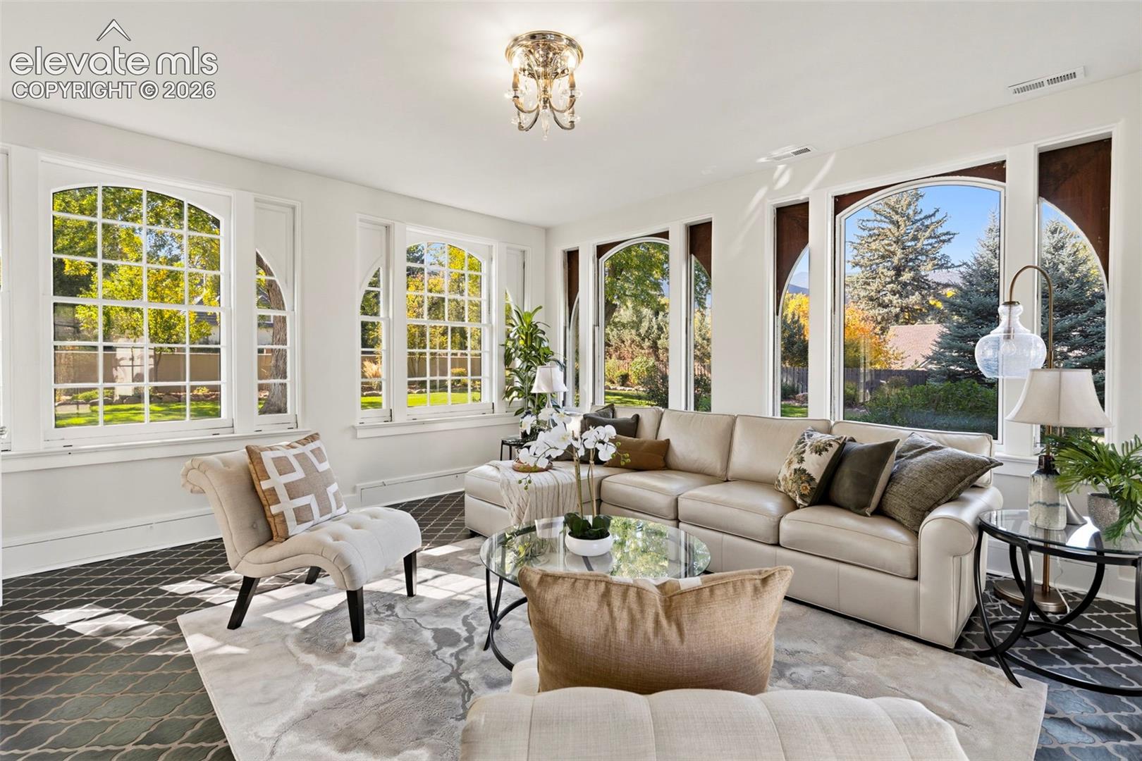 Sun-filled living space featuring expansive arched windows, intricate grid detailing, and patterned tile flooring