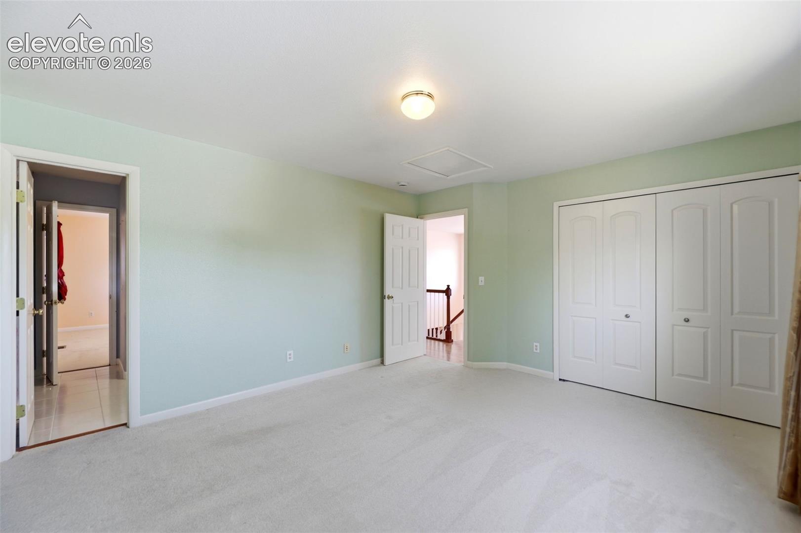 Spacious room with light green walls and neutral carpeting