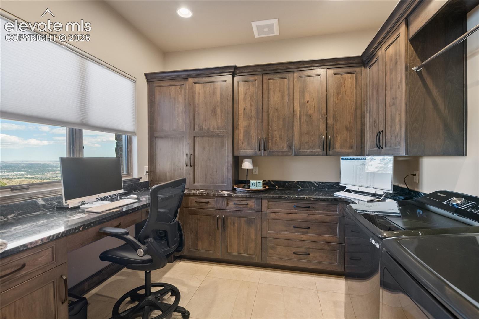 Who said laundry day had to be boring? Dual-purpose office and laundry room with custom cabinetry, granite counters, and sweeping city views from the desk.