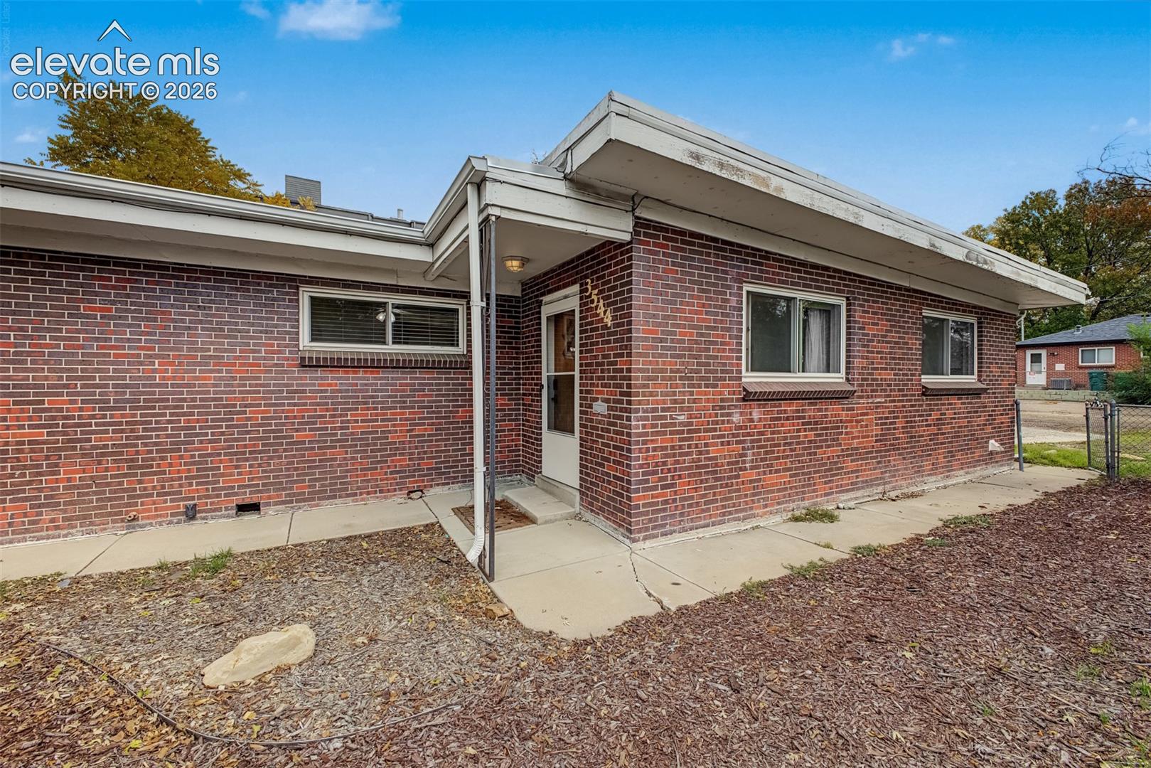 Mid-century modern architectural style featuring a low-pitched roofline, red brick exterior, concrete entry porch, and multi-pane windows
