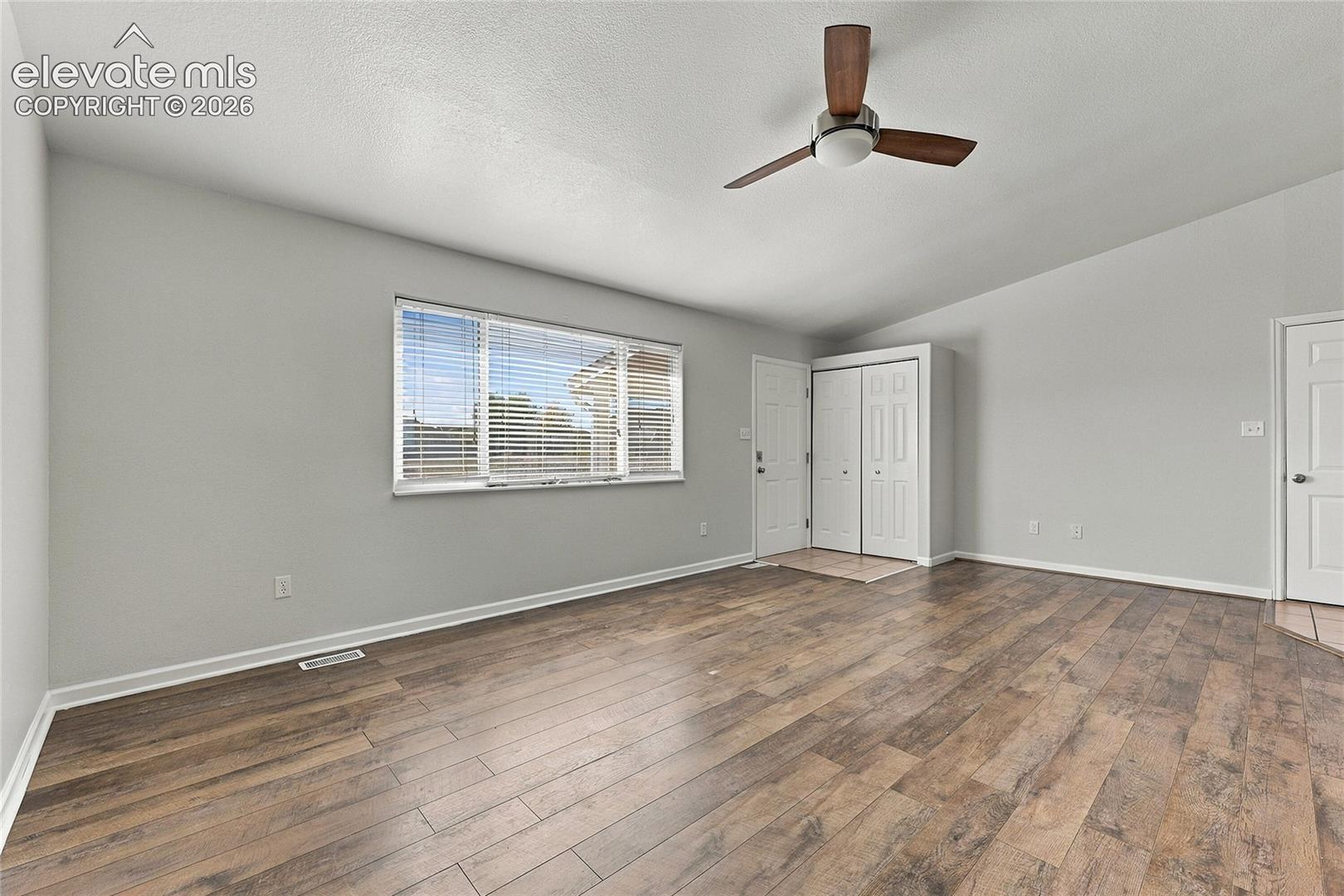 Wood-finish flooring, vaulted ceiling, multi-blade ceiling fan, and double-door reach-in closet
