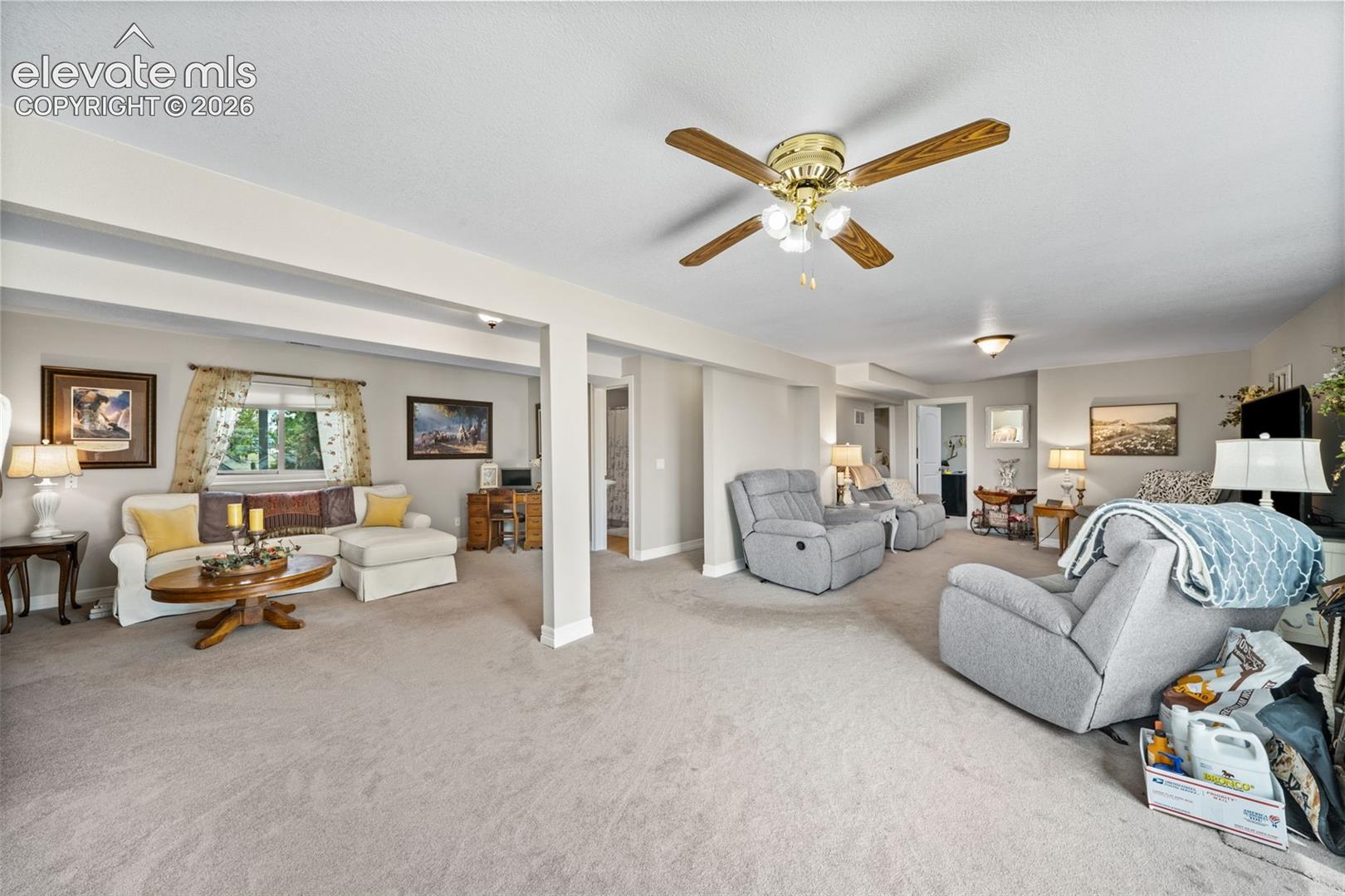 Spacious living area featuring light-toned carpeting, recessed lighting, and a ceiling fan with wood-finish blades