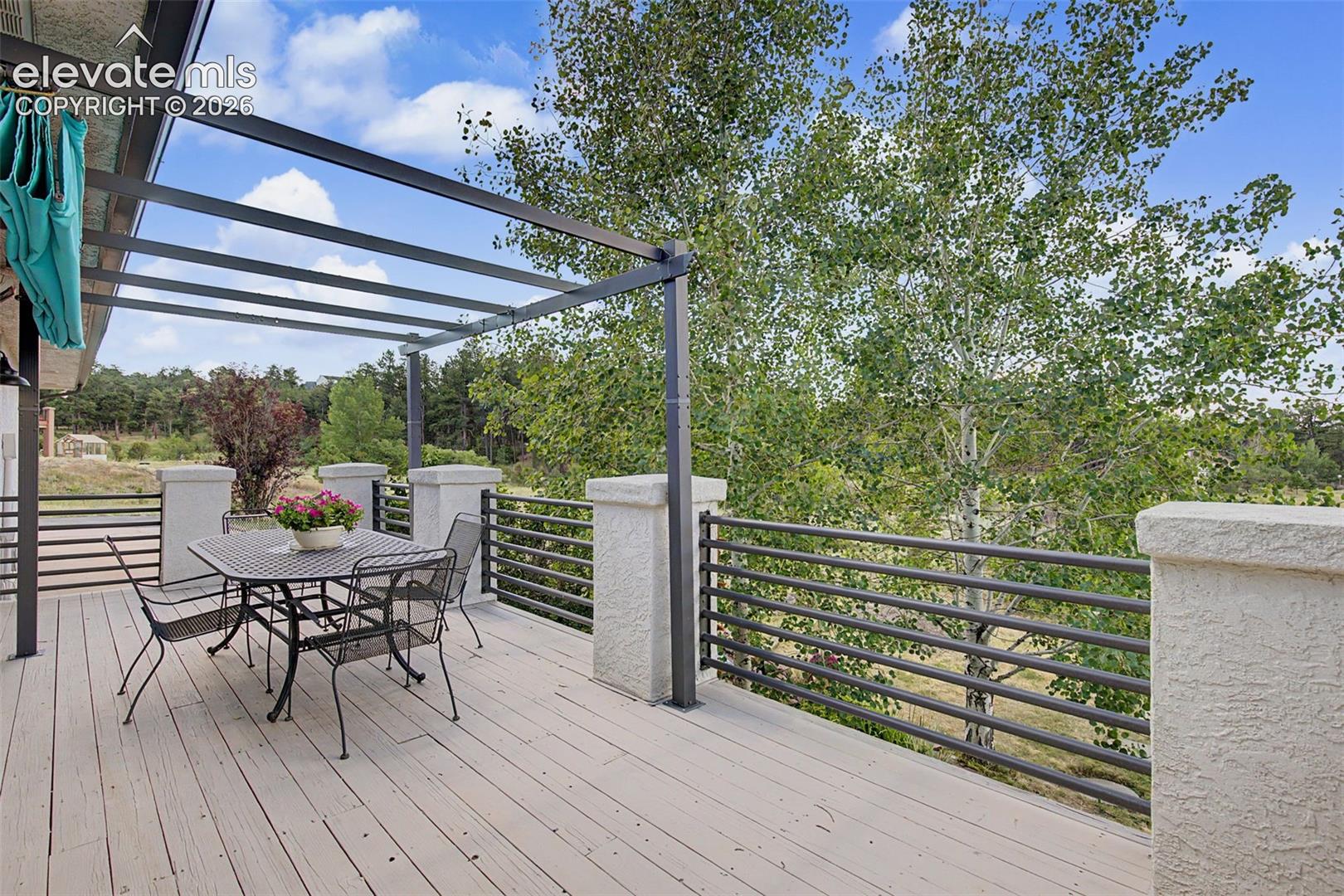 Expansive outdoor deck featuring wood-finish flooring, a contemporary metal pergola, and sleek horizontal railings