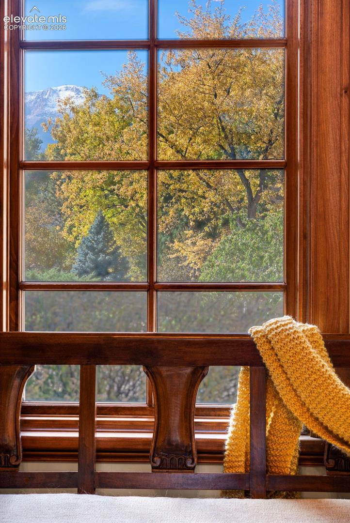 Multi-pane window with wood framing featuring intricate millwork and a backdrop of mountain scenery and mature trees