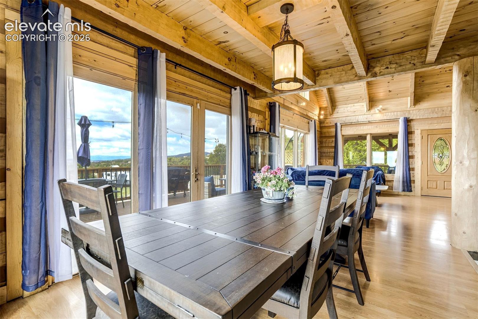 Spacious dining area featuring exposed wood beams and wood-finish flooring