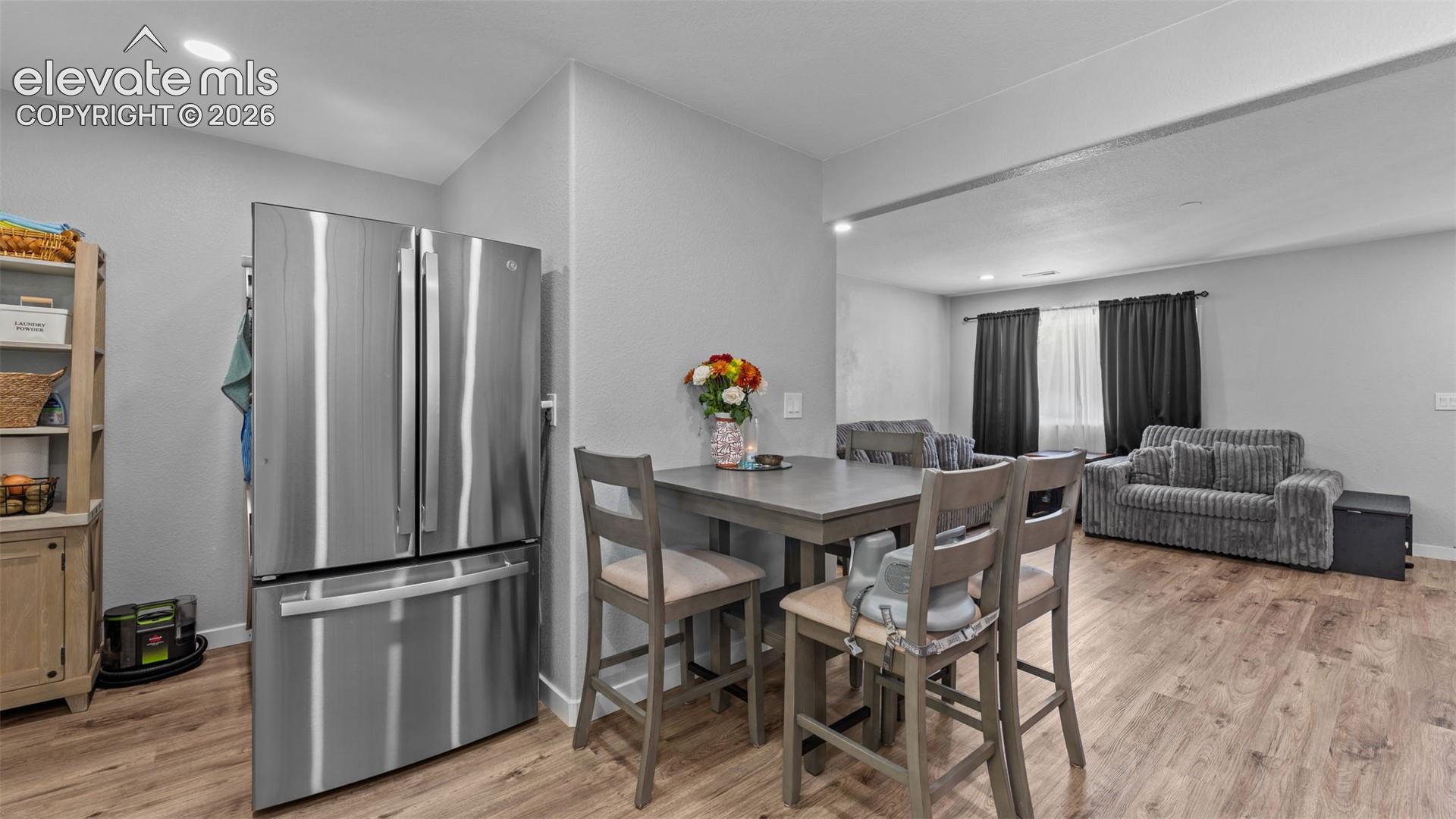 Stainless steel French-door refrigerator, wood-finish flooring, and recessed ceiling lighting
