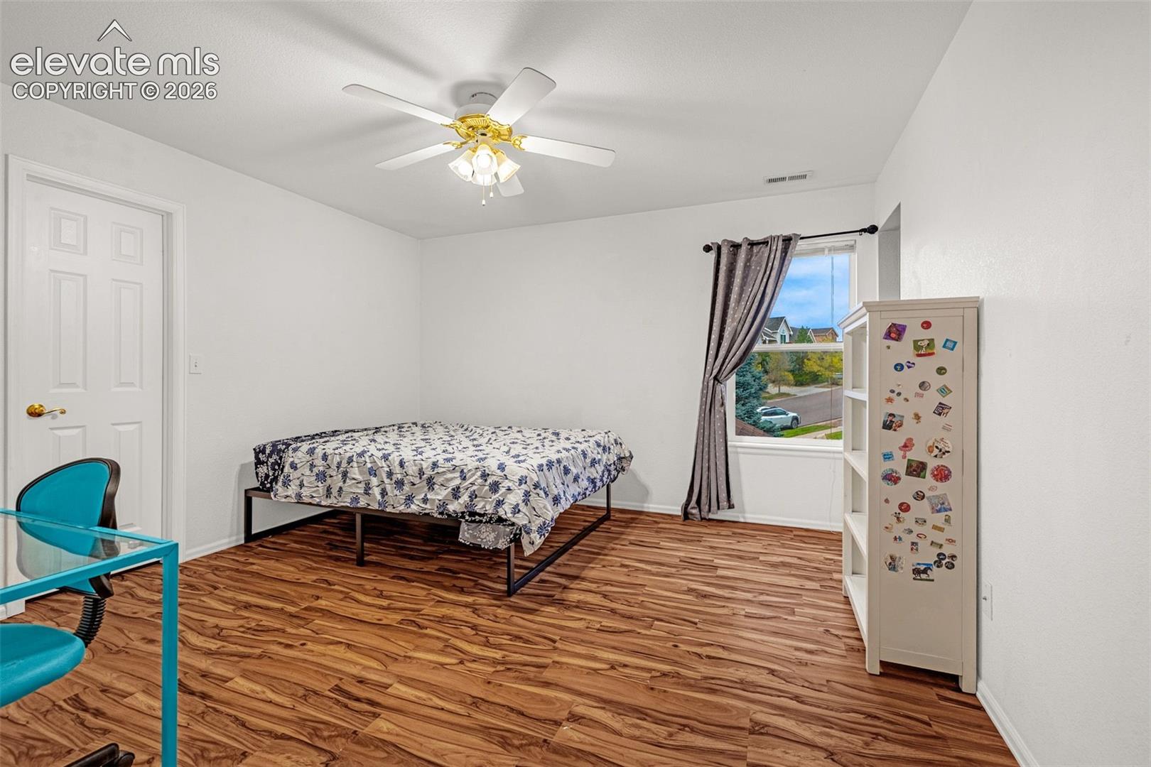Room featuring wood-finish flooring, a ceiling fan with integrated lighting, and white walls