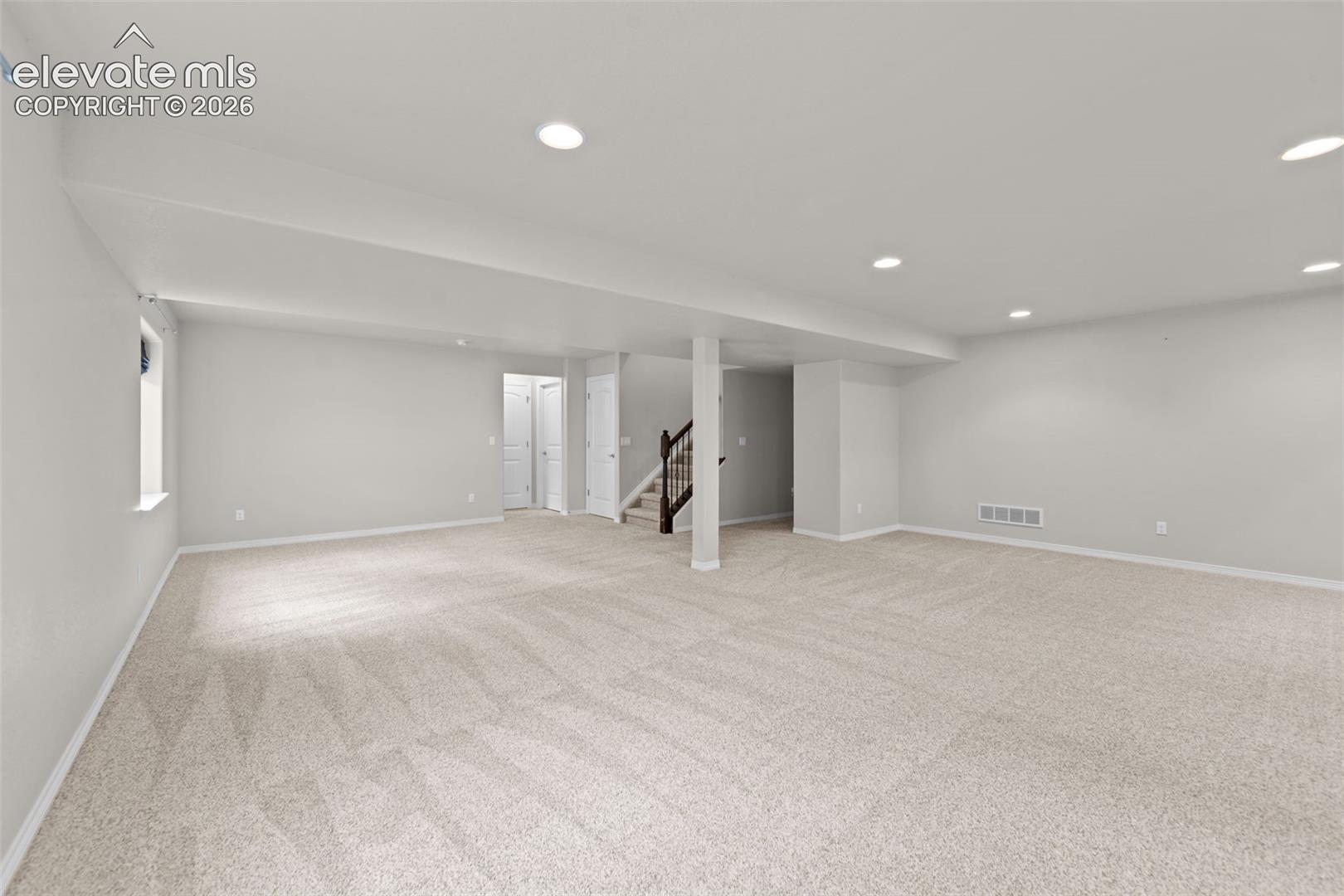 Expansive open room featuring plush carpeting, recessed lighting, and a neutral color palette
