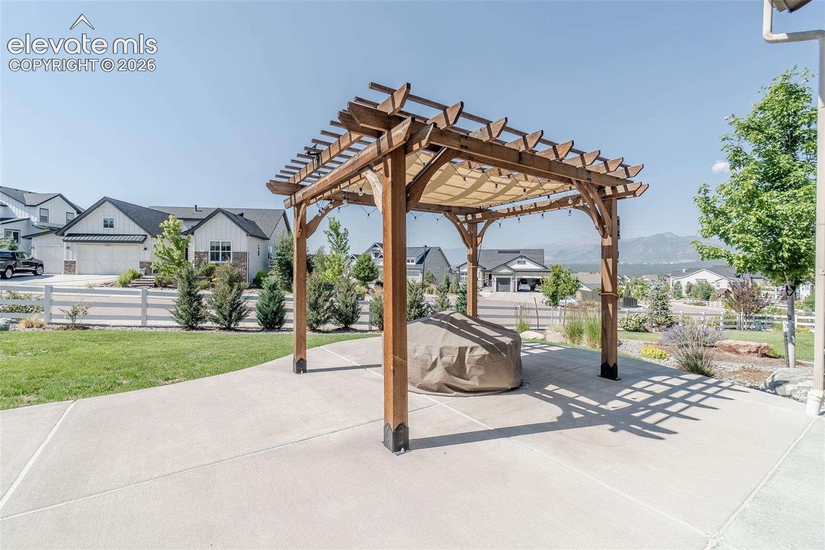Expansive concrete patio featuring a wood pergola with a fabric canopy
