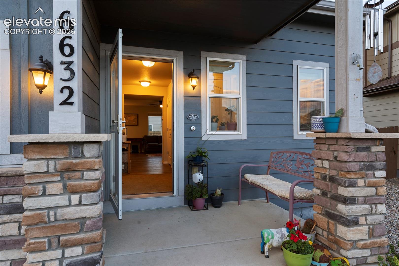 Inviting front entry featuring a concrete porch stacked stone pillar accents