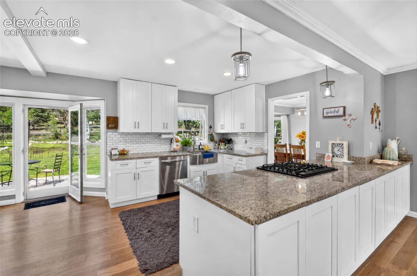 Kitchen featuring white cabinetry, a built-in cooktop, stainless steel dishwasher, and wood-finish flooring