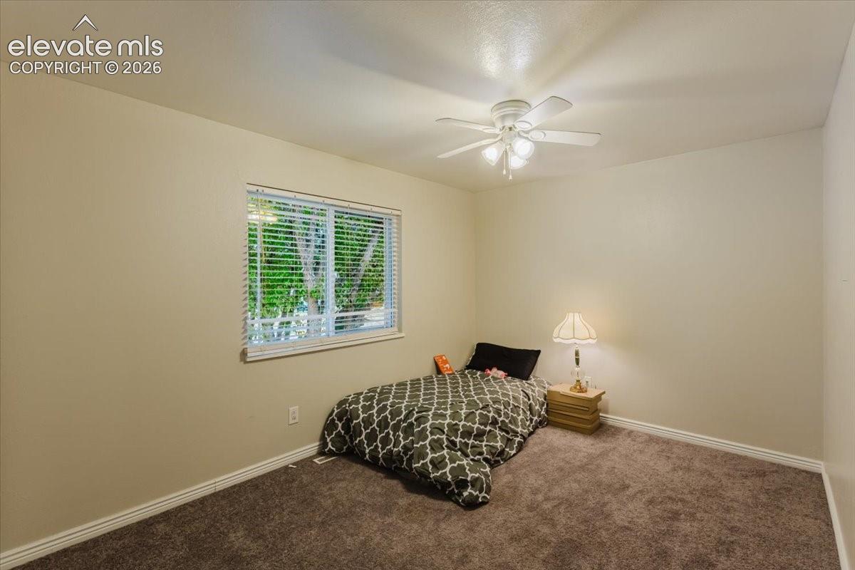 Bedroom featuring a window with blinds, a ceiling fan with integrated lighting, neutral wall tones, and carpet flooring