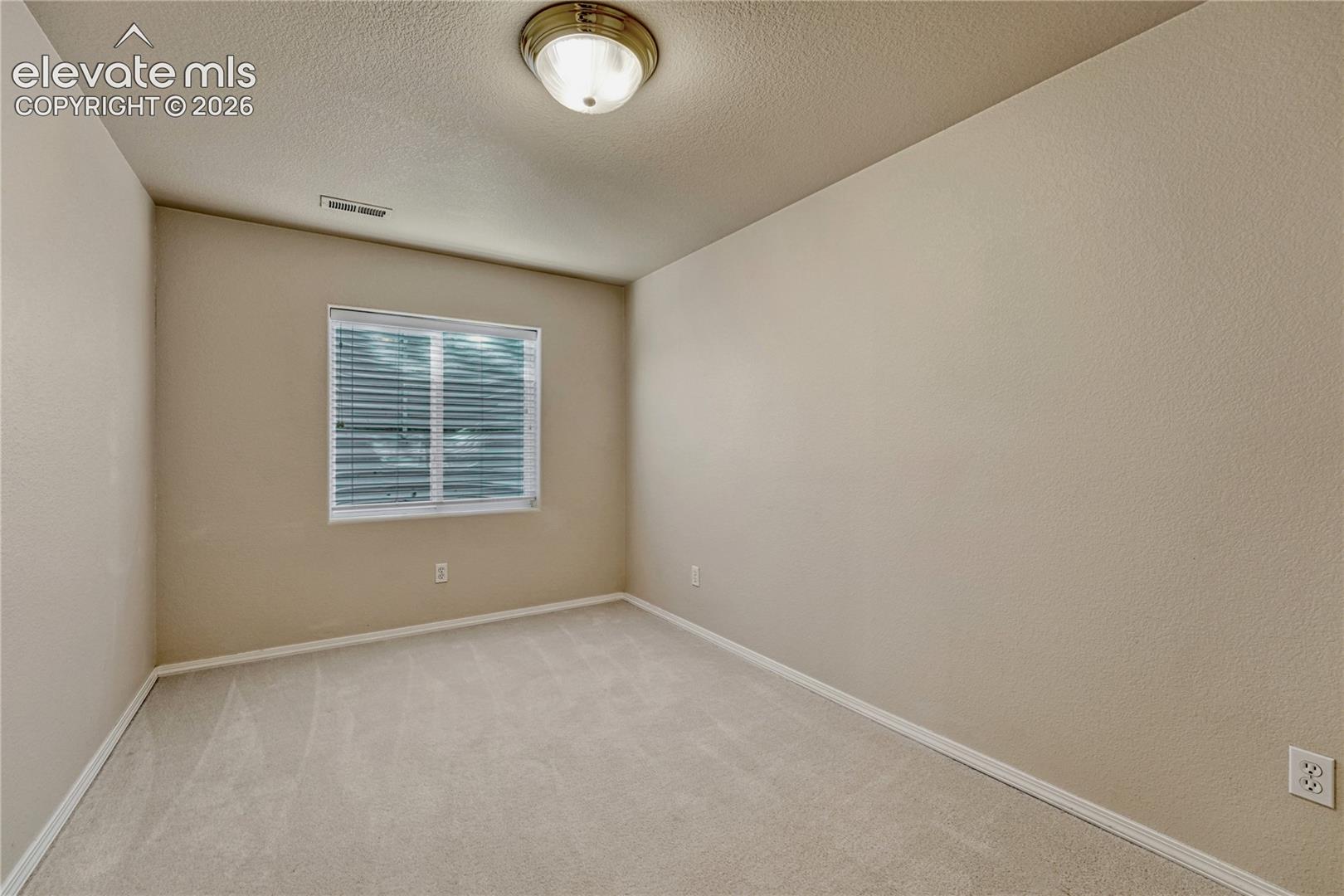 Sunlit basement bedroom equipped with an egress window and neutral decor, ready for your personalized touch
