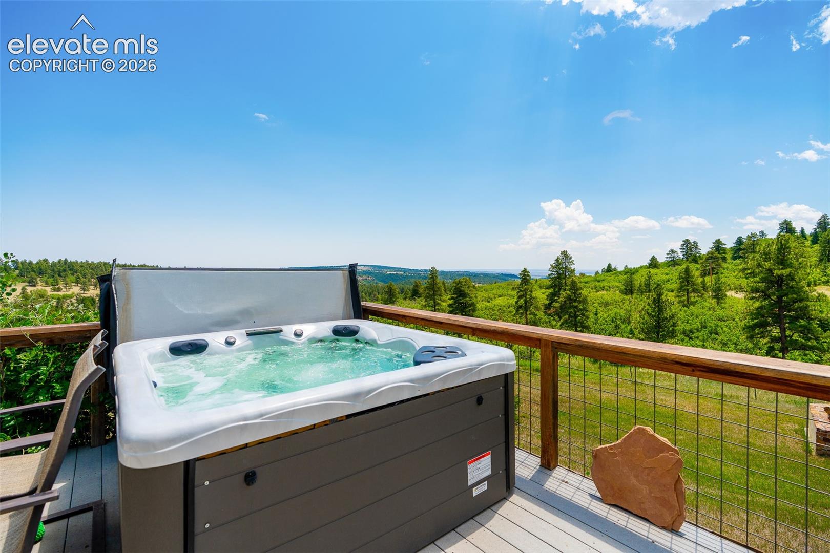 Wraparound deck with hot tub access from primary suite photographed June 2026