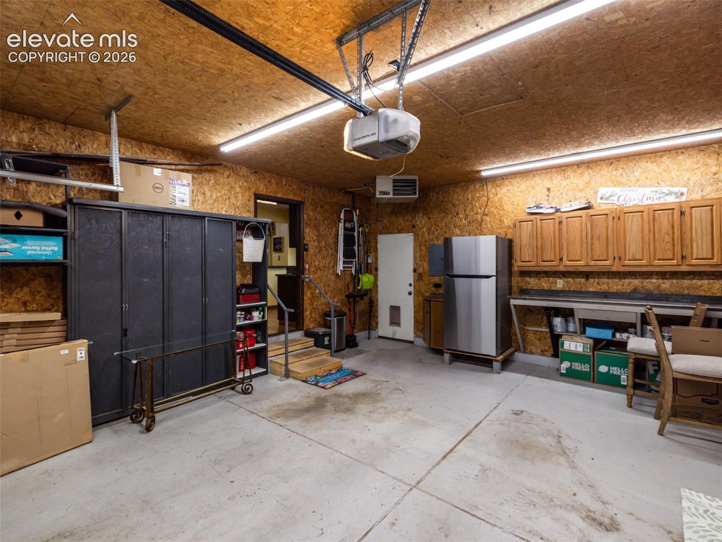 Concrete flooring with overhead fluorescent lighting, wood-paneled walls, and built-in wood cabinetry