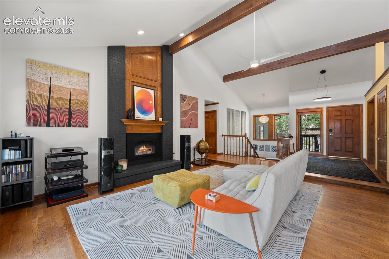 Living area featuring vaulted ceilings with exposed wood beams, a fireplace with a wood mantle and dark surround, wood-finish flooring, and recessed lighting