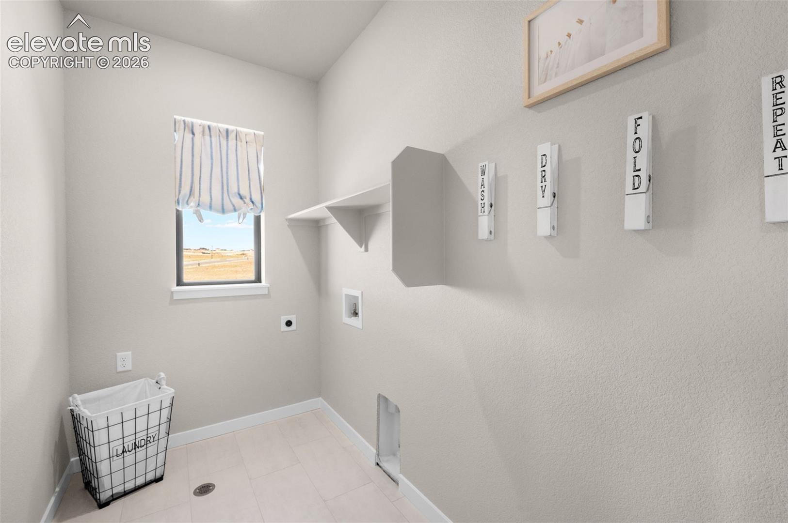 Laundry area featuring a window, built-in shelving, and light-toned flooring