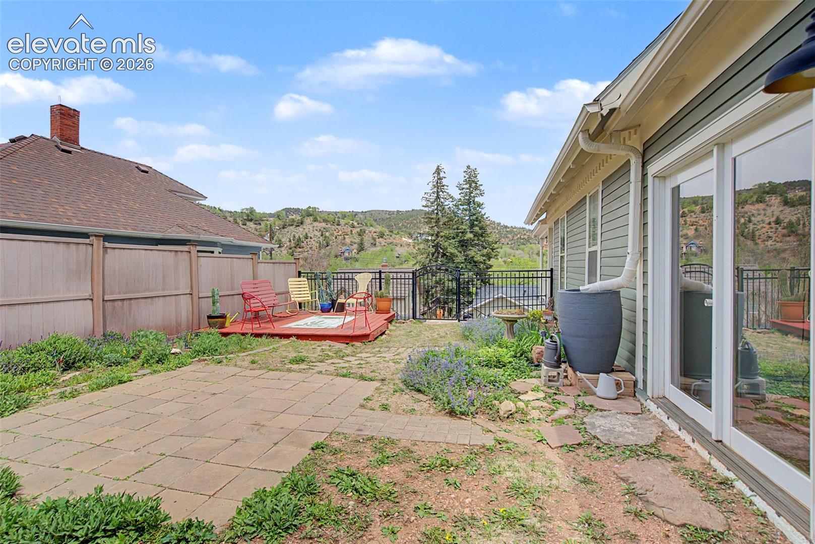 Outdoor living area featuring a wooden deck, a stone patio, and fencing