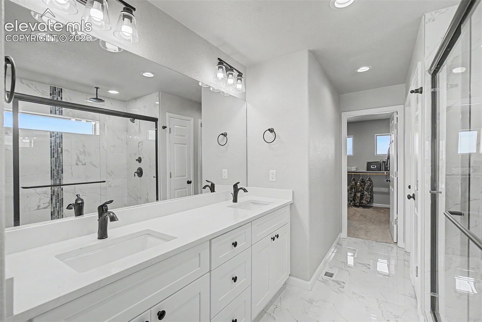 Spacious bathroom featuring a double vanity with white cabinetry, matte black fixtures, and a large wall-mounted mirror
