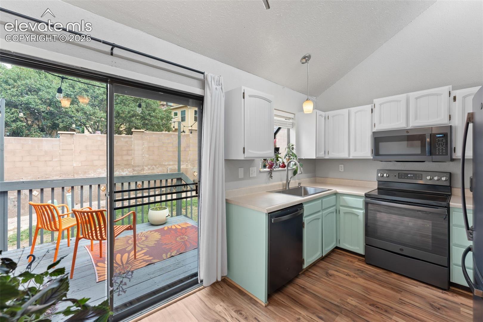 Kitchen featuring wood-finish flooring, white upper cabinetry, and light green lower cabinetry