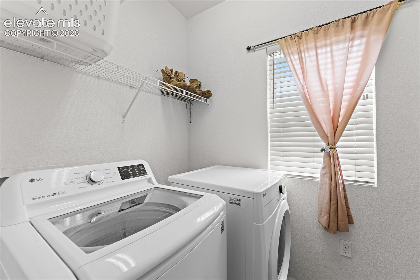 Laundry area featuring a top-load washer, a front-load dryer, and wall-mounted wire shelving under a window with horizontal blinds