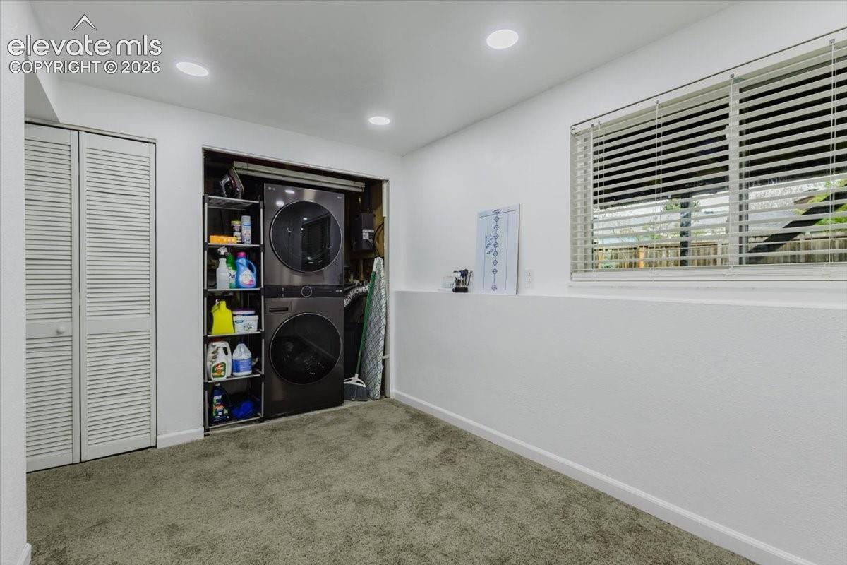 Dedicated laundry area featuring a stacked washer and dryer unit, integrated shelving, and recessed lighting