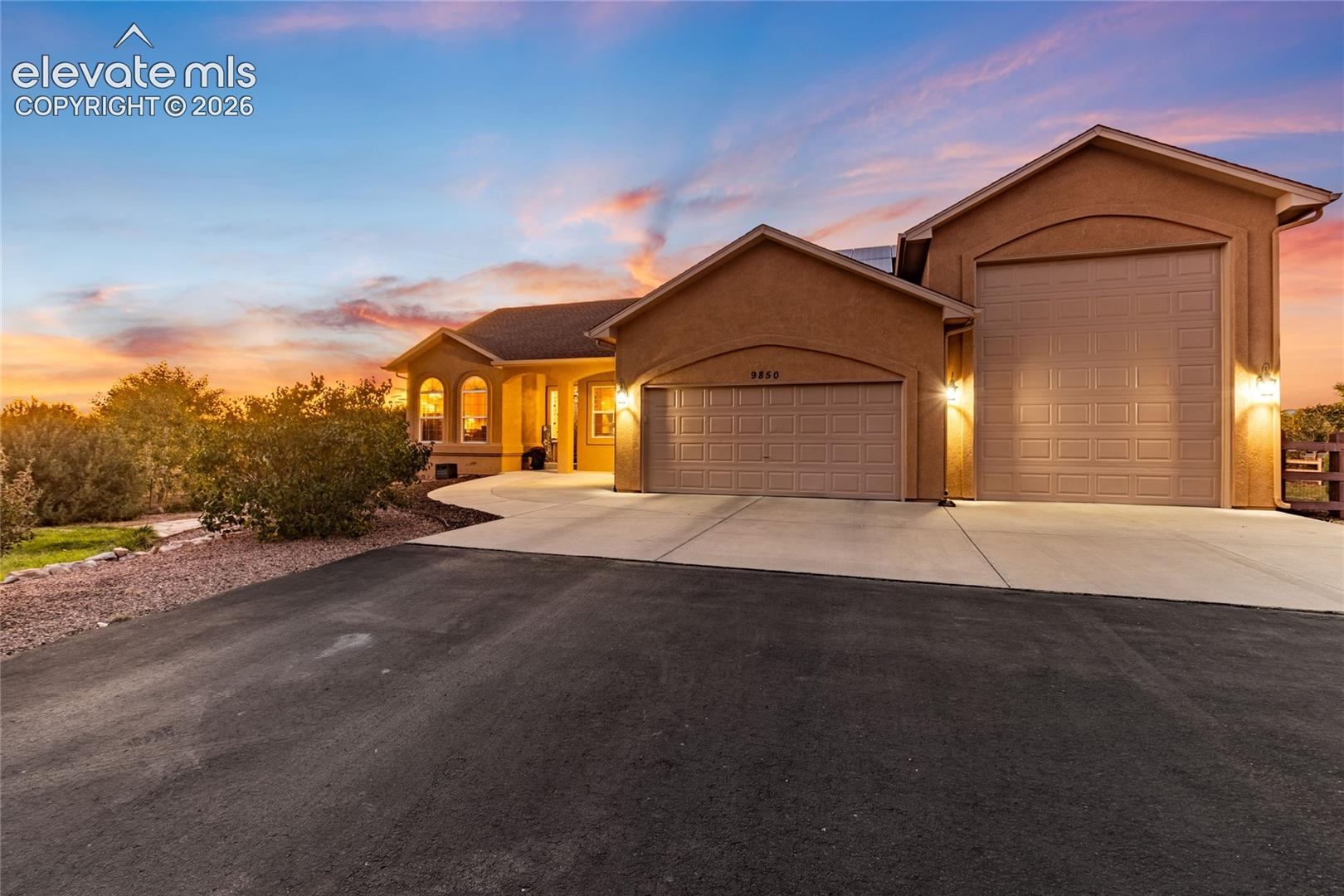 Stucco exterior featuring a two-car garage, high-clearance RV bay, concrete driveway, and arched entryway