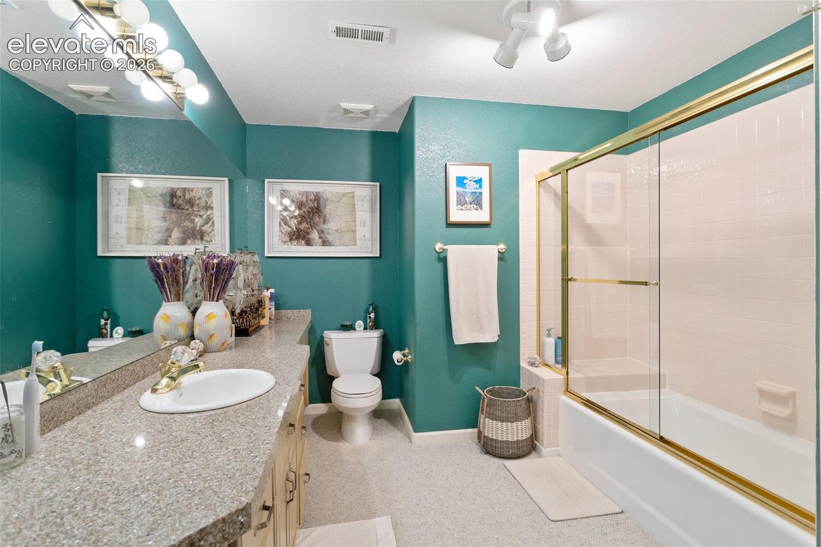 Bathroom featuring a double vanity with an oval basin, a gold-toned faucet, and a large mirror with strip lighting