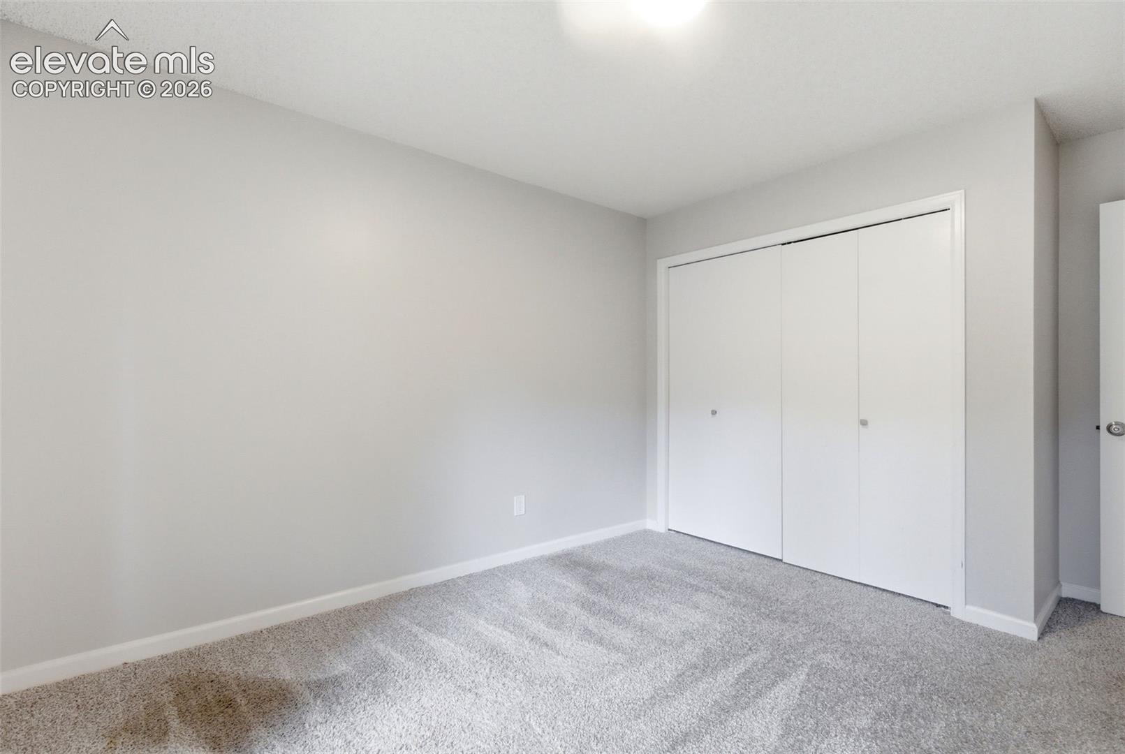 Spacious room featuring light gray wall paint and a plush gray carpet