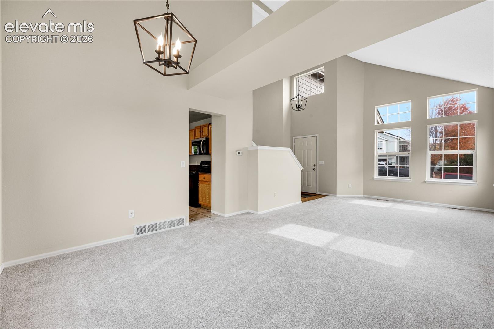 Vaulted ceilings, geometric metal pendant lighting, large multi-pane windows, and neutral carpeting