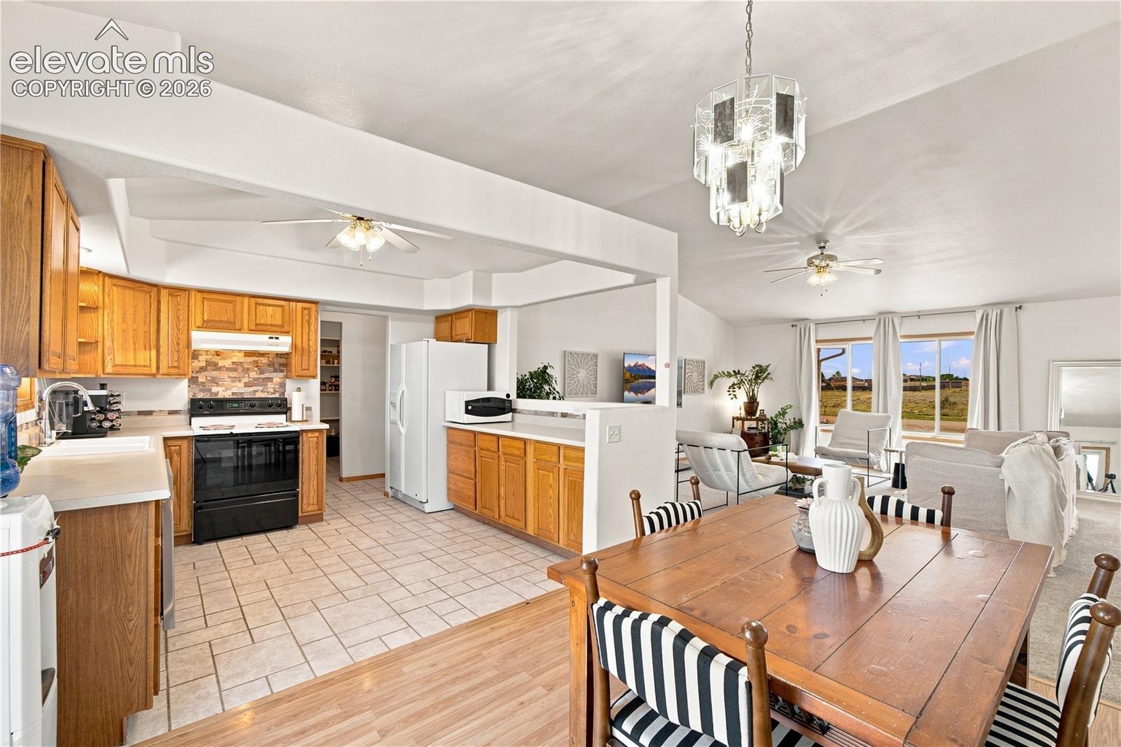 Open-concept kitchen and dining area featuring wood cabinetry, tile flooring, stainless steel appliances, and a spacious dining table with seating for multiple guests