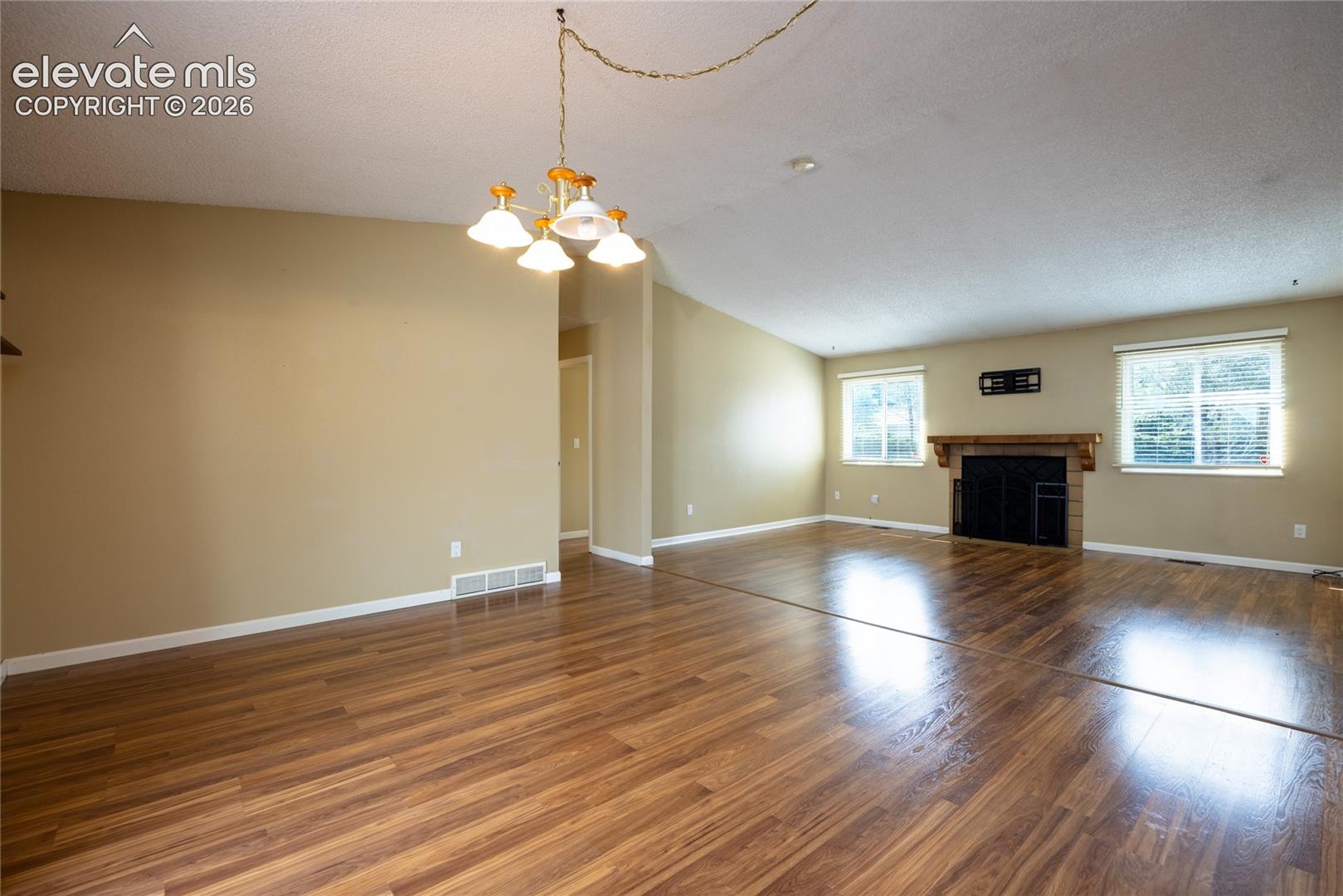 Wood-finish flooring throughout, recessed lighting, and a fireplace with a wood mantle and brick surround