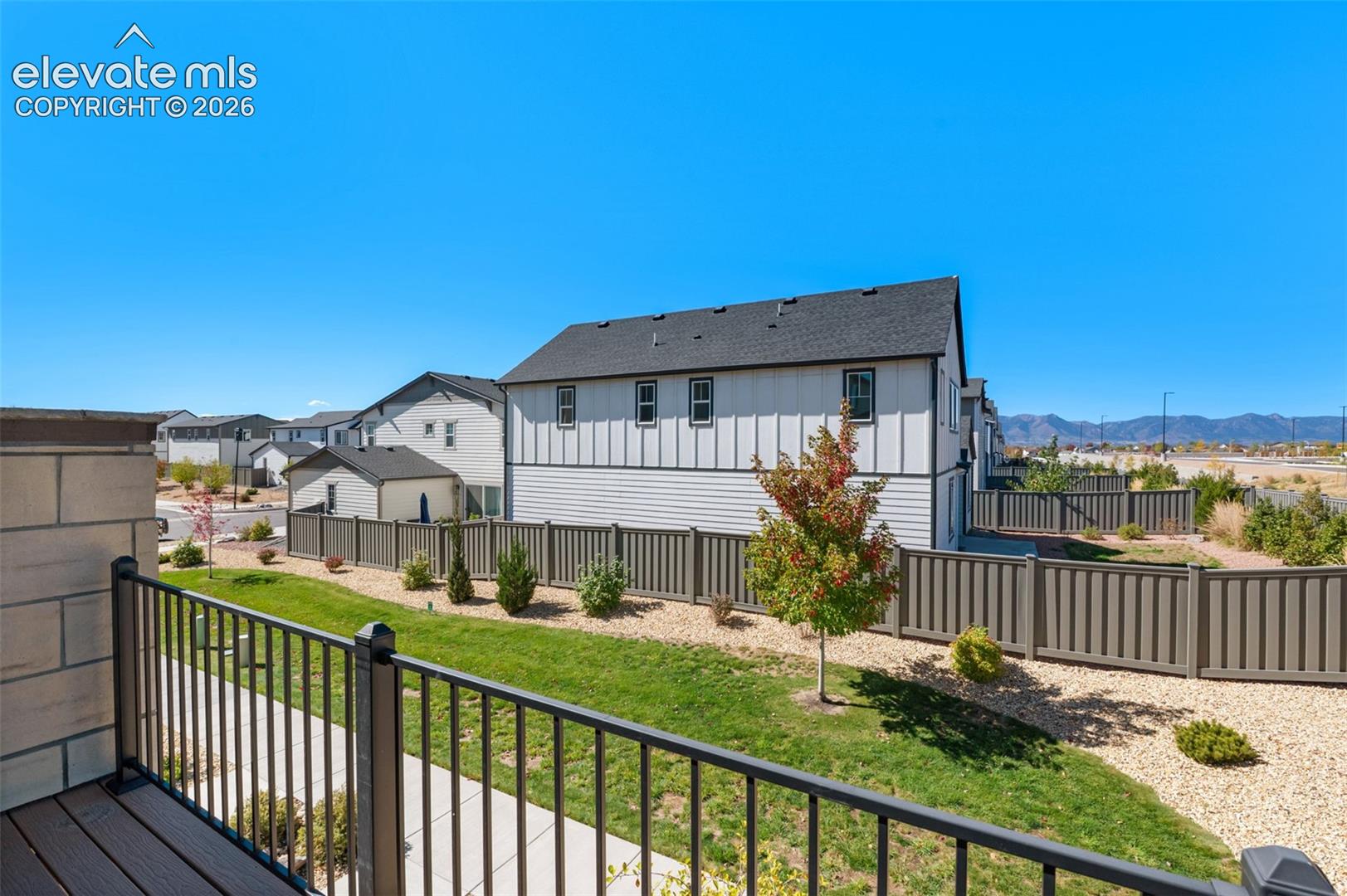 Balcony with dark metal railings, wood-finish decking, and mountain backdrop