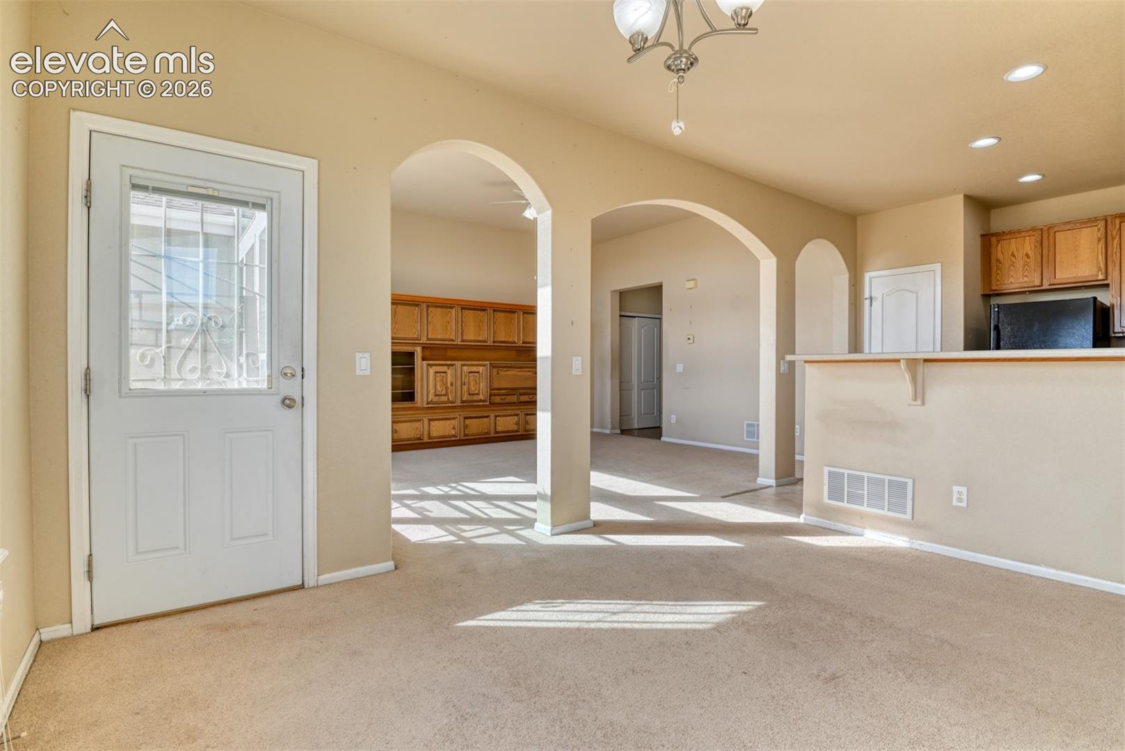 Interior featuring architectural arched entryways, built-in wooden cabinetry, a breakfast bar, recessed lighting, and a multi-pane glass entry door